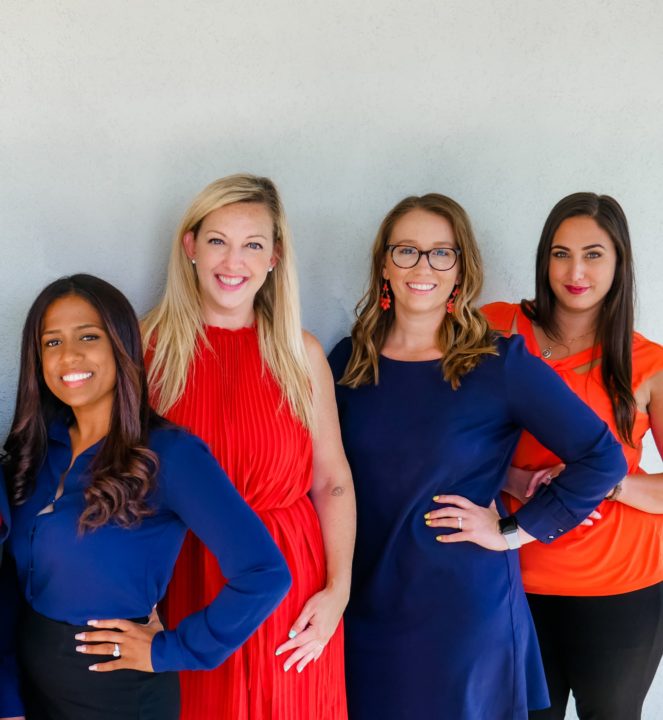 four females in orange and blue professional wear